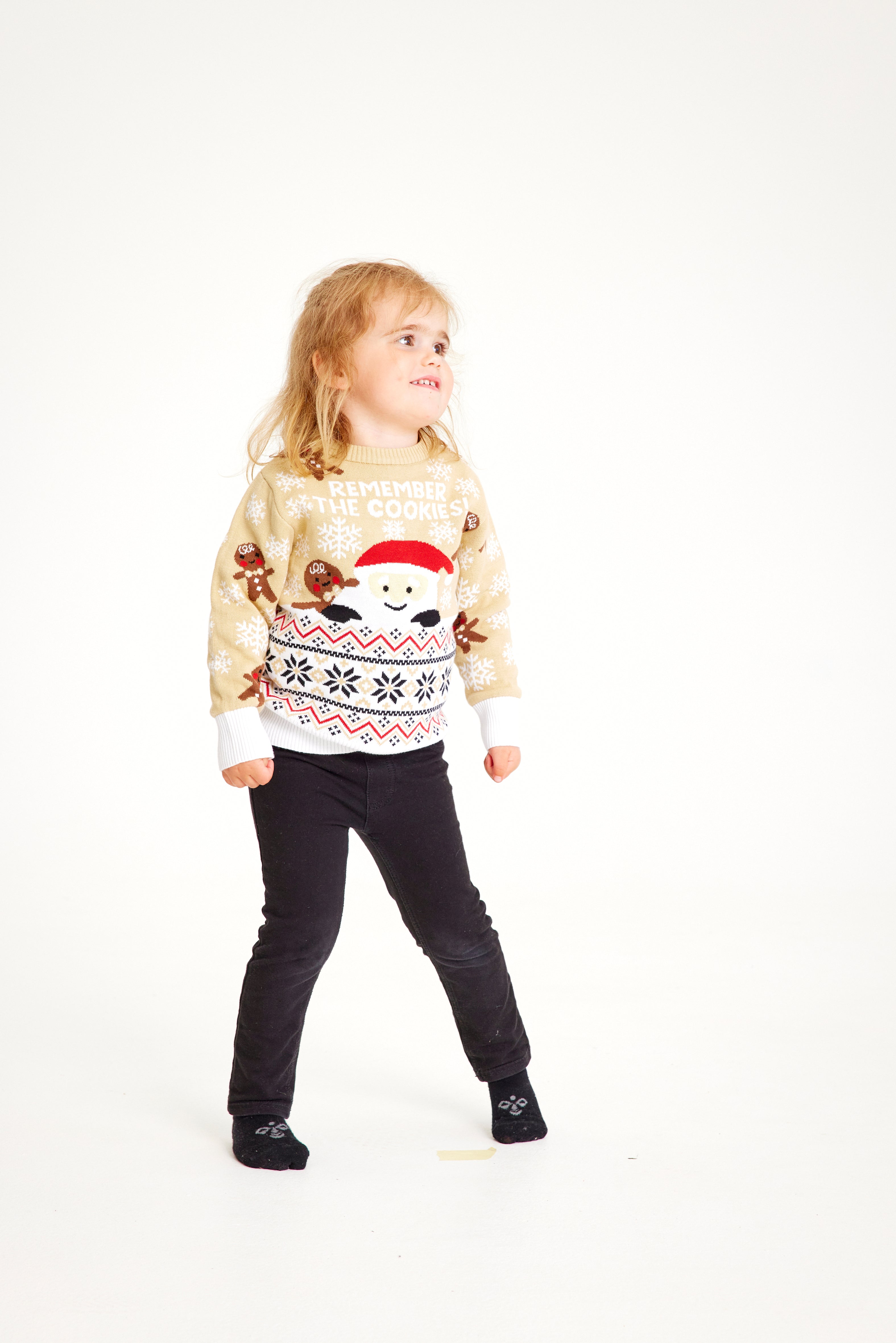 Et barn iført en beige julesweater.